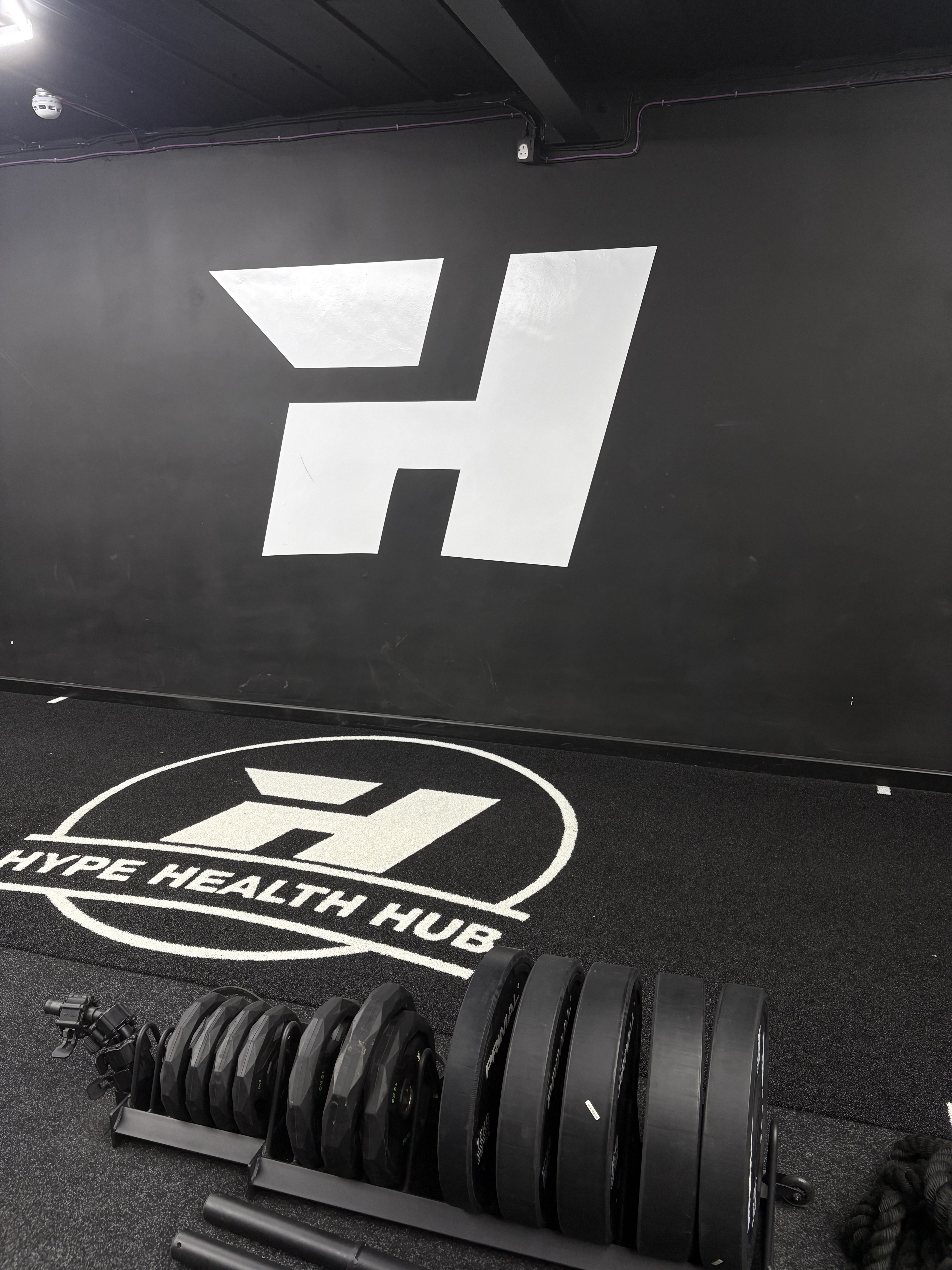 Hype Health Hub wall logo above the dumbbell rack
